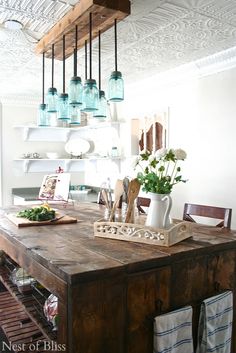 a wooden table topped with vases filled with flowers and greenery on top of it