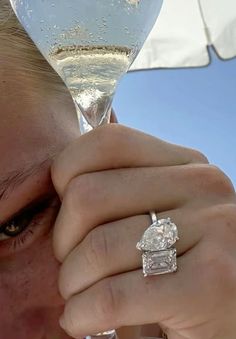 a close up of a person holding a wine glass with a diamond ring on it