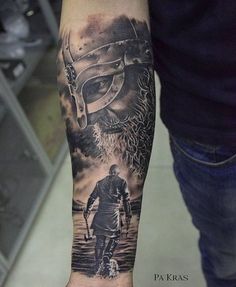 a man's arm with a black and grey tattoo on it, depicting a viking warrior