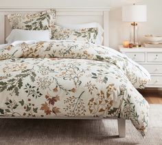 a bed with a green floral comforter and matching pillows in a white bedroom setting