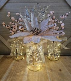 three mason jars with lights and flowers in them