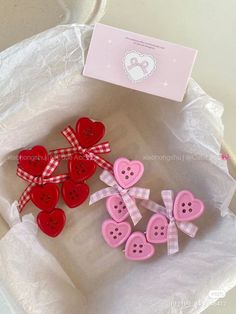 some pink and red buttons sitting on top of a white paper bag next to a card