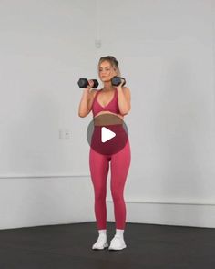 a woman in pink workout clothes holding two dumbbells