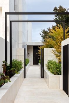 an entrance to a building with plants and trees in the foreground on either side