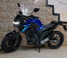 a blue motorcycle parked in front of a brick wall