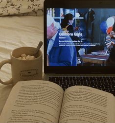 an open book sitting on top of a laptop computer next to a cup of coffee