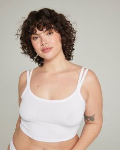 a woman with curly hair wearing a white tank top