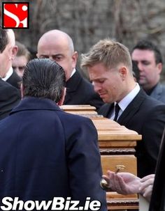 a group of men standing around a wooden casket