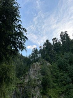 there is a boat in the water near some rocks and trees on the side of the river