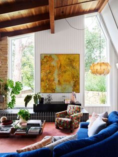 a living room filled with furniture and a painting on the wall above it's windows