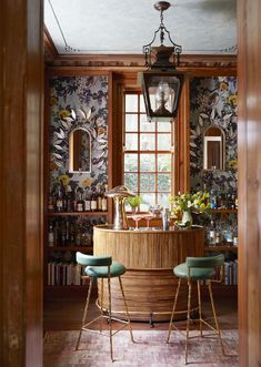 a bar with stools in front of a window and wallpapered walls behind it