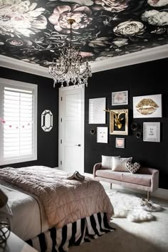 a bedroom decorated in black and white with flowers on the ceiling, chandelier