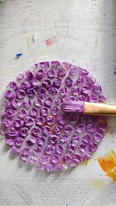 a paintbrush is being used to make purple flowers