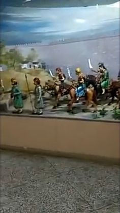 a group of figurines that are on the side of a wall with water in the background