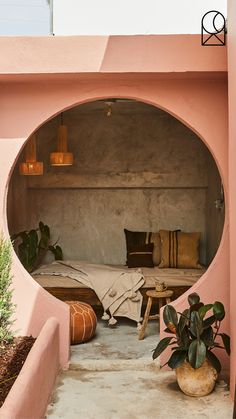 a bed sitting inside of a pink wall next to a potted plant