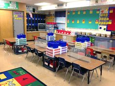 a classroom filled with lots of desks and colorful bins on top of them