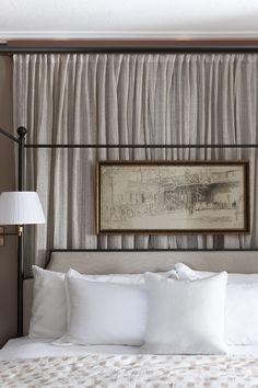 a bed with white sheets and pillows under a painting on the wall above headboard