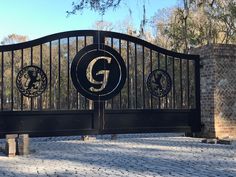 an iron gate with two lions on it and the letter g at the top is in front of a brick wall