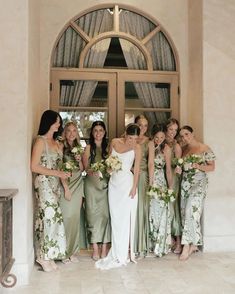 a group of women standing next to each other in front of a doorway with flowers