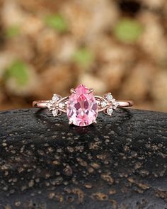 a pink diamond ring sitting on top of a rock