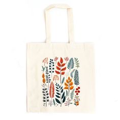 a tote bag with an orange and green leaf design on the front, sitting against a white background