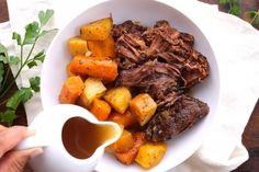 a bowl filled with meat, potatoes and carrots next to a white saucer