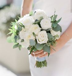 a bride holding a bouquet of white roses