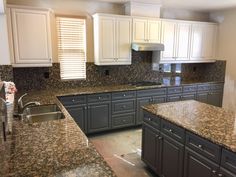 an empty kitchen with granite counter tops and white cupboards on either side of the sink