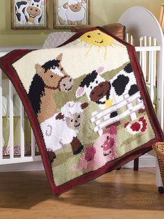 a baby crib with a blanket that has farm animals on it and sheep in the background