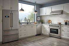 a kitchen with white cabinets, stainless steel appliances and wood flooring is seen in this image