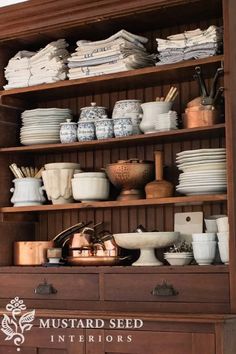 a wooden cabinet filled with lots of white dishes and bowls on top of it's shelves