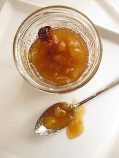 a spoon with some food in it sitting on a white plate next to a glass jar