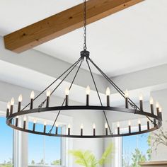 a chandelier hanging from the ceiling in a dining room with windows and potted plant