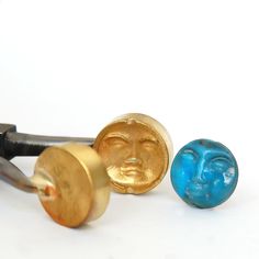 three different types of ear plugs with faces on them, one gold and the other blue