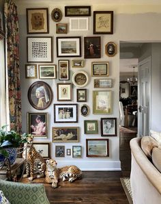 a living room filled with lots of framed pictures on the wall next to a couch