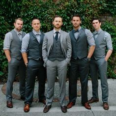 a group of men standing next to each other in front of a green plant wall