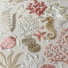 an embroidered pattern with seahorses and corals on white fabric, as well as gold sequins