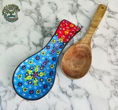 two wooden spoons sitting next to each other on a marble counter top, one with an ornate design