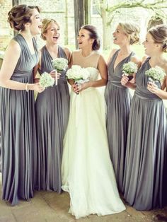 a group of women standing next to each other in front of a window holding bouquets