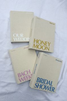 four books are laying on a white sheet with the words our wedding, honey moon, and bridal shower