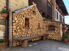 a house made out of logs with windows and flowers in pots on the outside wall