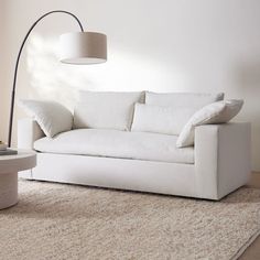 a white couch sitting on top of a rug next to a lamp