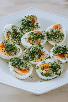 a white plate topped with deviled eggs covered in herbs