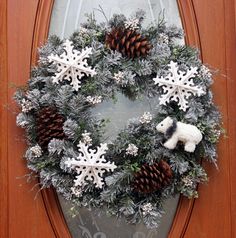 a wreath with snowflakes, pine cones and a polar bear on it is hung on the front door