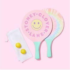 two ping pong paddles sitting on top of a pink surface next to a pair of lemons