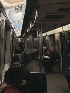 people are sitting on the subway train and looking at their phones