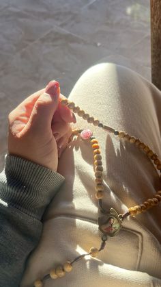 a person holding a rosary in their hand while sitting on a couch next to the water