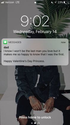 a man sitting on top of a white toilet next to a plant and texting