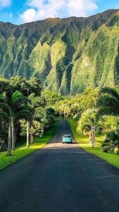 a car is driving down the road in front of mountains