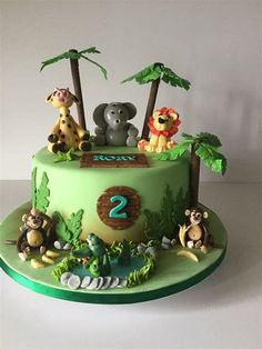 a green cake with animals on it and numbers 2 in the middle, sitting on top of a table